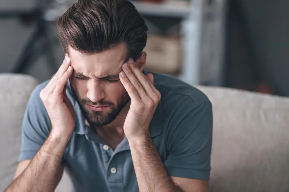 man-with-migraine-headache-massaging-his-temples-and-frowning