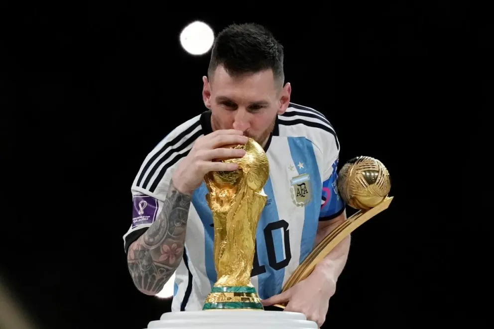 Lionel Messi acaricia el sueño: la Copa del Mundo. En segundo plano, sostiene el premio al mejor jugador de Qatar 2022. 