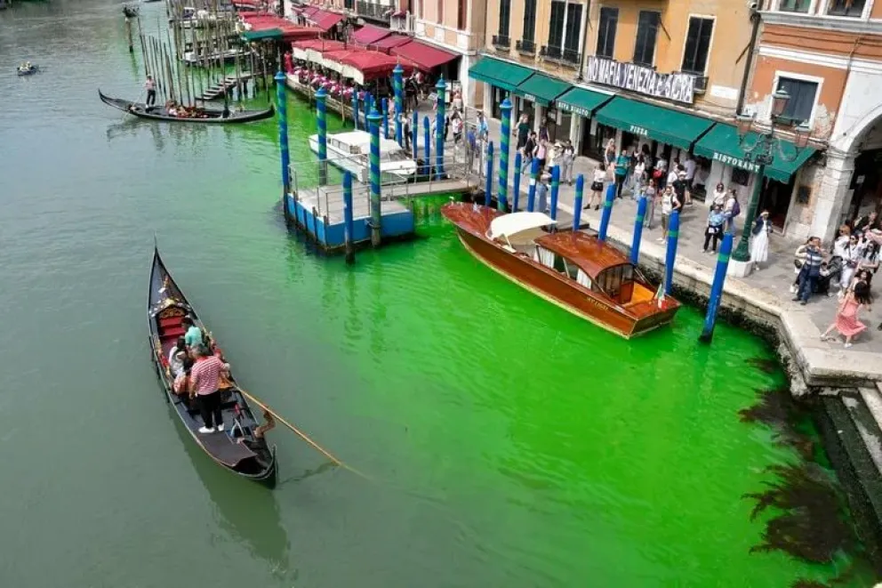 Una góndola navega por el histórico Gran Canal de Venecia, manchado por un líquido verde, el domingo 28 de mayo de 2023.